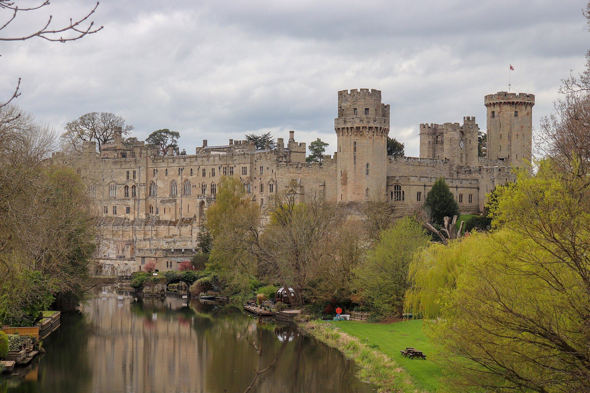 Warwick Castle viewed from Castle Bridge, its medieval towers and ramparts reflected in the River Avon